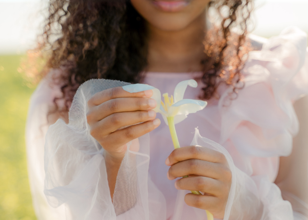 Person holding a flower with a blurred natural background